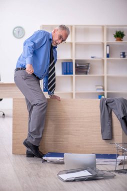 Ofisteki aşırı işten memnun olmayan yaşlı bir erkek işçi.