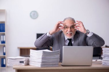 Ofisteki aşırı işten memnun olmayan yaşlı bir erkek işçi.