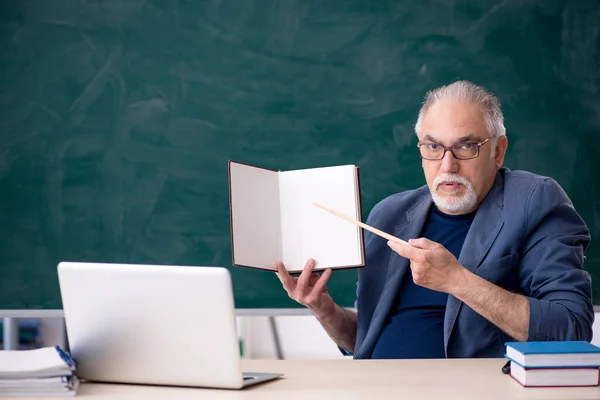 Starý učitel drží knihu ve třídě — Stock fotografie