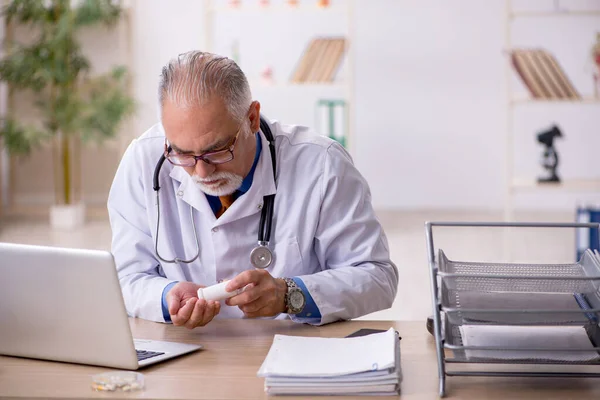 Old male doctor working in the clinic — Stock Photo, Image