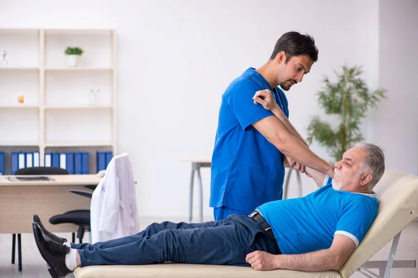 Old male patient visiting young male doctor — Stock Photo, Image