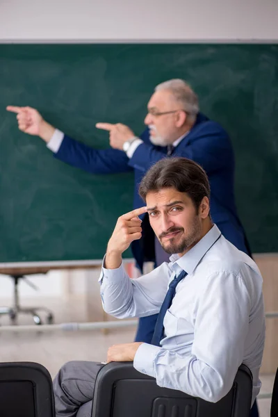 Öreg férfi tanár és fiatal férfi diák a zöld tábla előtt — Stock Fotó