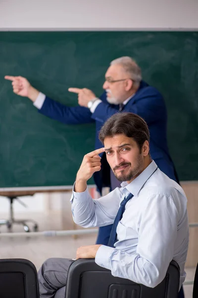 Alter männlicher Lehrer und junger männlicher Student vor grünem Brett — Stockfoto