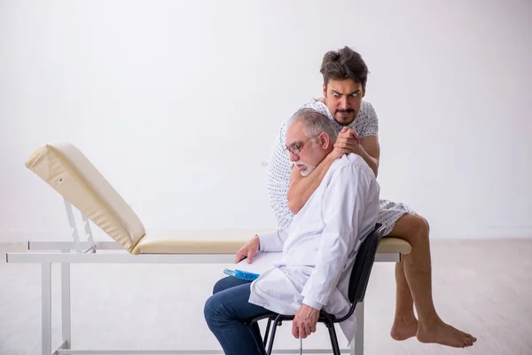 Velho médico psiquiatra masculino examinando jovem paciente masculino — Fotografia de Stock