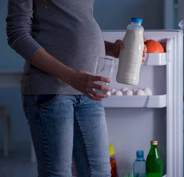 Mulher grávida perto de geladeira à procura de alimentos e lanches à noite — Fotografia de Stock