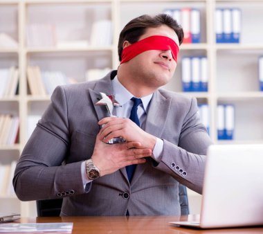 Ofiste masasında oturan gözü bağlı iş adamı.