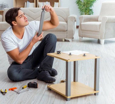 Adam evde mobilya montajı yapıyor.