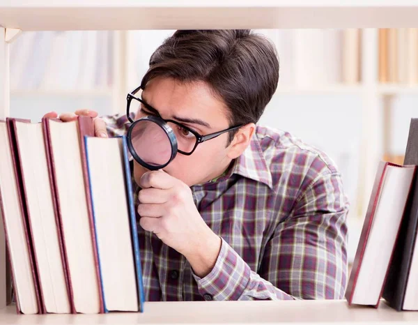 Молодой студент ищет книги в библиотеке колледжа — стоковое фото