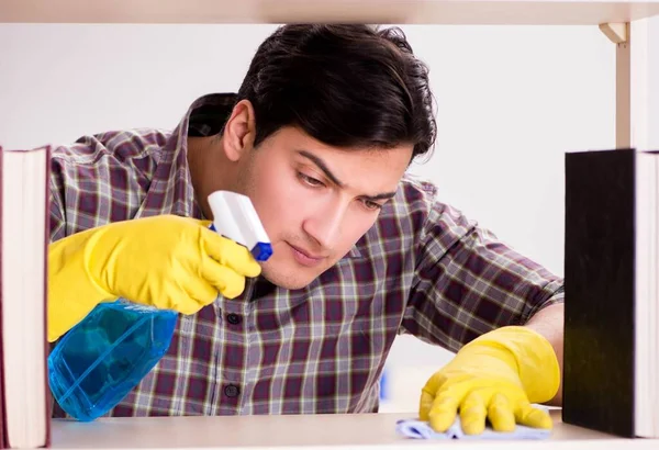 Kitaplıktaki tozları temizleyen adam