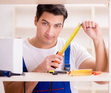 İşçi adam montaj kitaplığını tamir ediyor