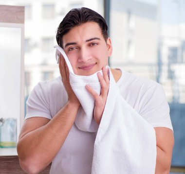 Genç yakışıklı adam yüz kremi sürüyor.