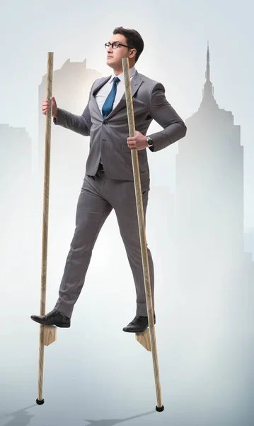 Businessman walking on stilts - standing out from the crowd — Stock Photo, Image