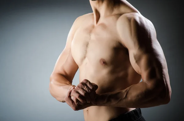 Hombre musculoso posando en estudio oscuro — Foto de Stock