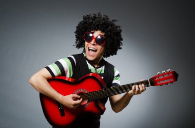 Komik saç kesimi ve gitarı olan adam.
