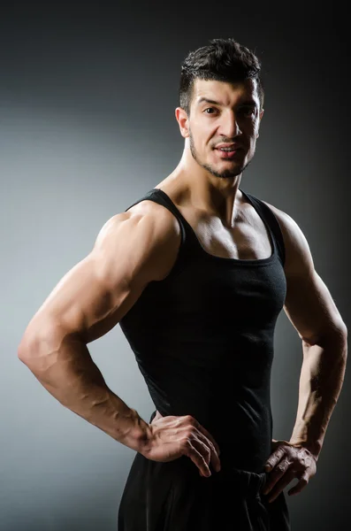 Muscular man posing in dark studio — Stock Photo, Image