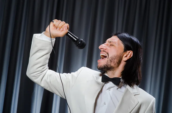 Man singing in front of curtain in karaoke concept — Stock Photo, Image