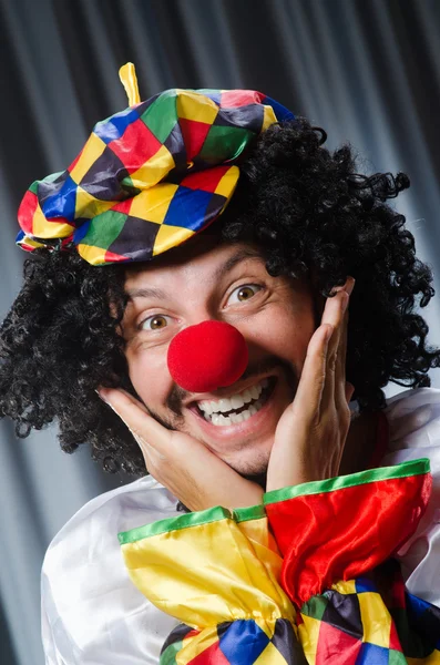 Lustiger Clown mit humorvollem Konzept gegen Vorhang — Stockfoto