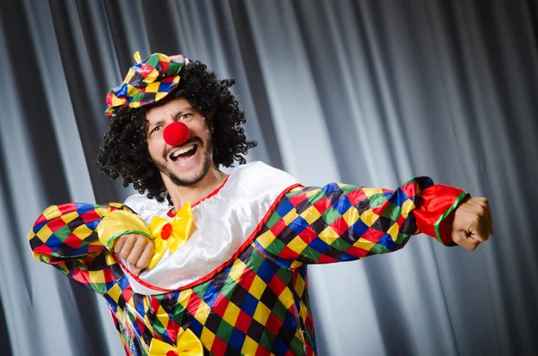 Lustiger Clown mit humorvollem Konzept gegen Vorhang — Stockfoto