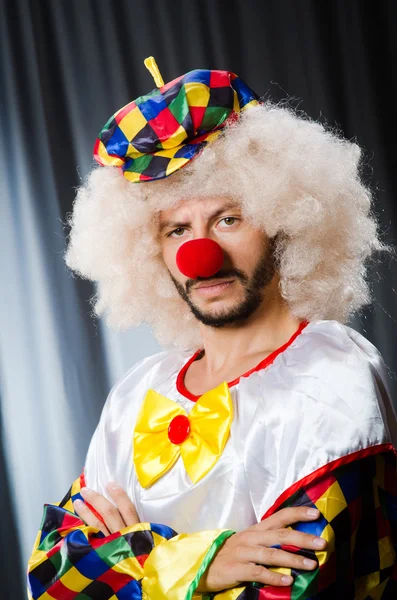 Lustiger Clown mit humorvollem Konzept gegen Vorhang — Stockfoto