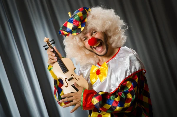 Funny clown plyaing violin against curtain — Stock Photo, Image