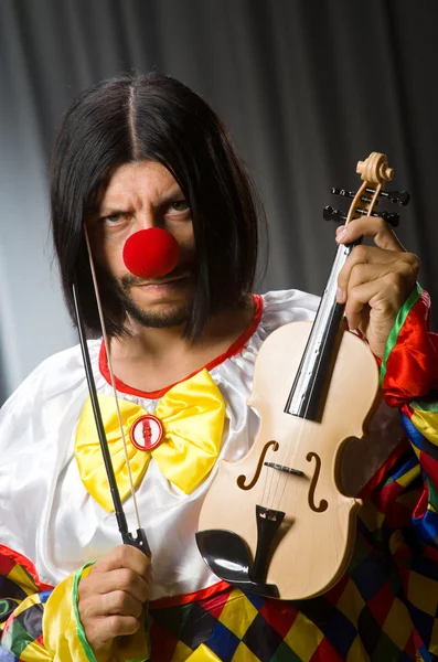 Grappige clown plyaing viool tegen gordijn — Stockfoto