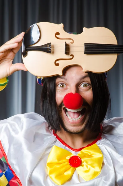 Funny clown plyaing violin against curtain — Stock Photo, Image