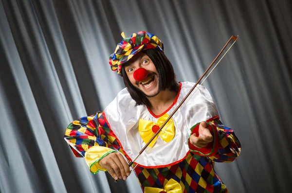 Funny clown plyaing violin against curtain — Stock Photo, Image