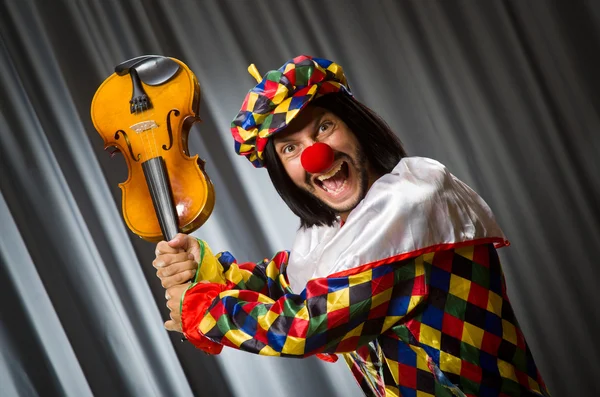 Engraçado palhaço plyaing violino contra cortina — Fotografia de Stock