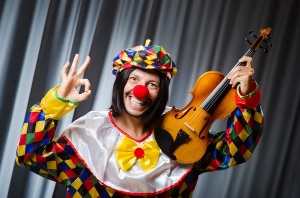 Grappige clown plyaing viool tegen gordijn — Stockfoto