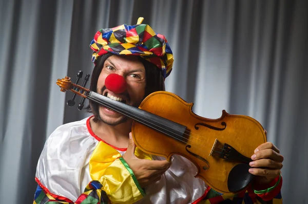 Engraçado palhaço plyaing violino contra cortina — Fotografia de Stock