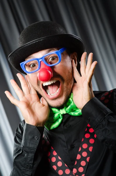 Rolig clown i humoristiskt koncept mot gardin — Stockfoto