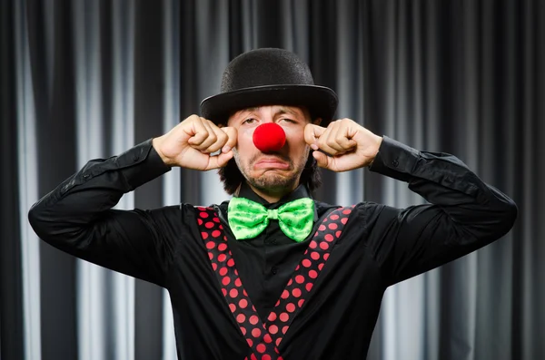 Lustiger Clown mit humorvollem Konzept gegen Vorhang — Stockfoto