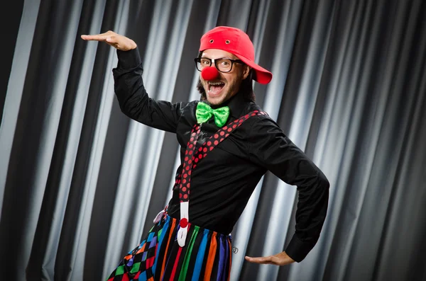 Clown divertente nel concetto umoristico contro tenda — Foto Stock