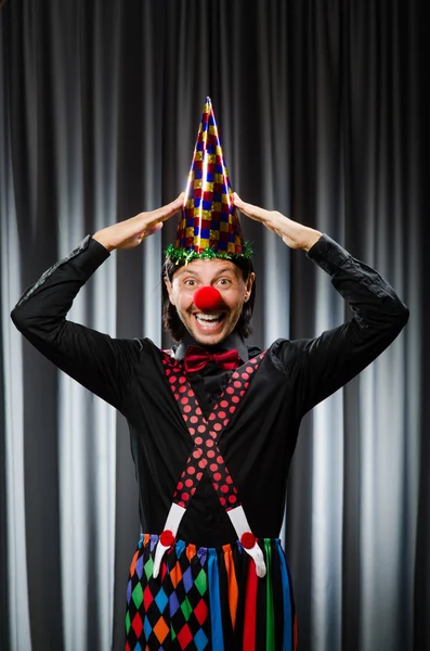 Lustiger Clown mit humorvollem Konzept gegen Vorhang — Stockfoto