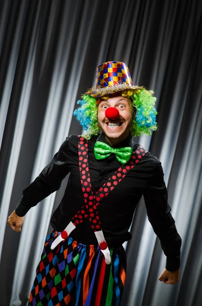 Lustiger Clown mit humorvollem Konzept gegen Vorhang — Stockfoto