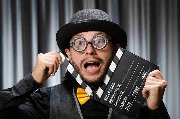 Homem engraçado com placa de filme contra cortina — Fotografia de Stock