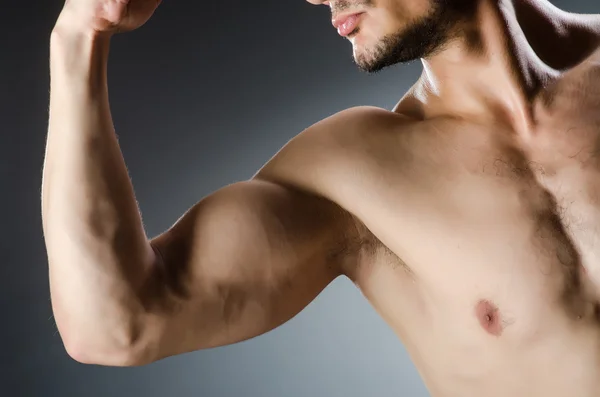 Muscular man posing in dark studio — Stock Photo, Image