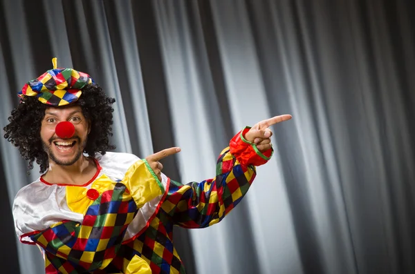 Payaso divertido en concepto humorístico contra cortina — Foto de Stock