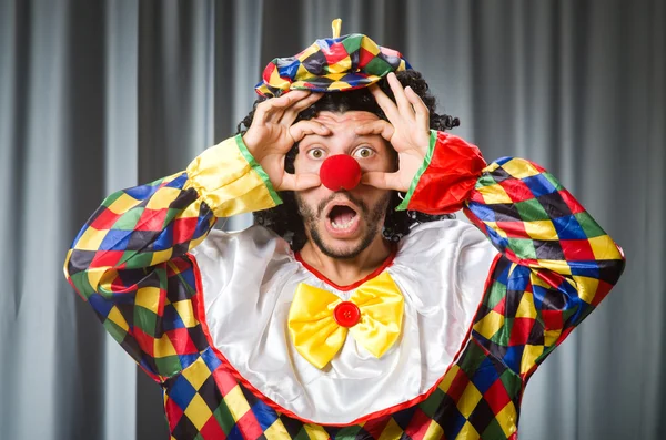 Lustiger Clown mit humorvollem Konzept gegen Vorhang — Stockfoto