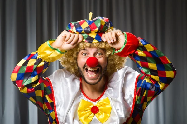 Lustiger Clown mit humorvollem Konzept gegen Vorhang — Stockfoto