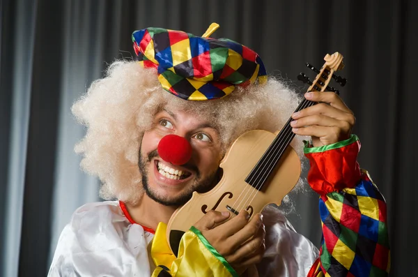 Grappige clown plyaing viool tegen gordijn — Stockfoto