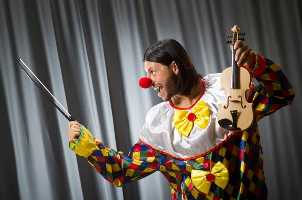 Funny clown plyaing violin against curtain — Stock Photo, Image