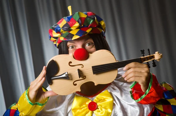 Engraçado palhaço plyaing violino contra cortina — Fotografia de Stock