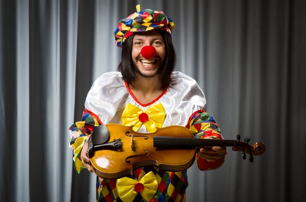 Funny clown plyaing violin against curtain — Stock Photo, Image