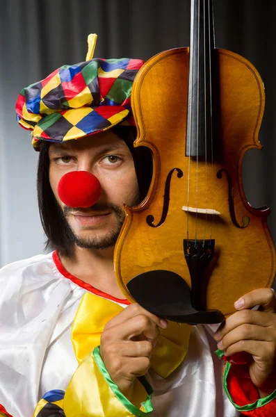 Lustiger Clown spielt Geige gegen Vorhang — Stockfoto