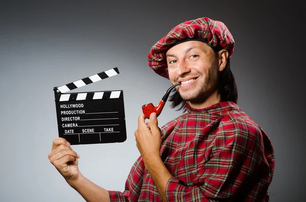 Funny scotsman with movie board and smoking pipe — Stock Photo, Image