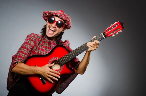 Roliga scotsman spela röd gitarr — Stockfoto
