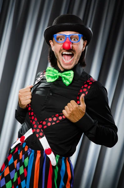 Lustiger Clown mit humorvollem Konzept gegen Vorhang — Stockfoto