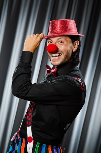 Lustiger Clown mit humorvollem Konzept gegen Vorhang — Stockfoto