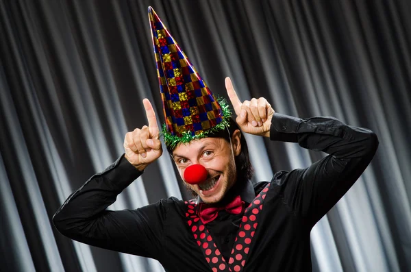Смешной клоун в юмористической концепции против занавески — стоковое фото